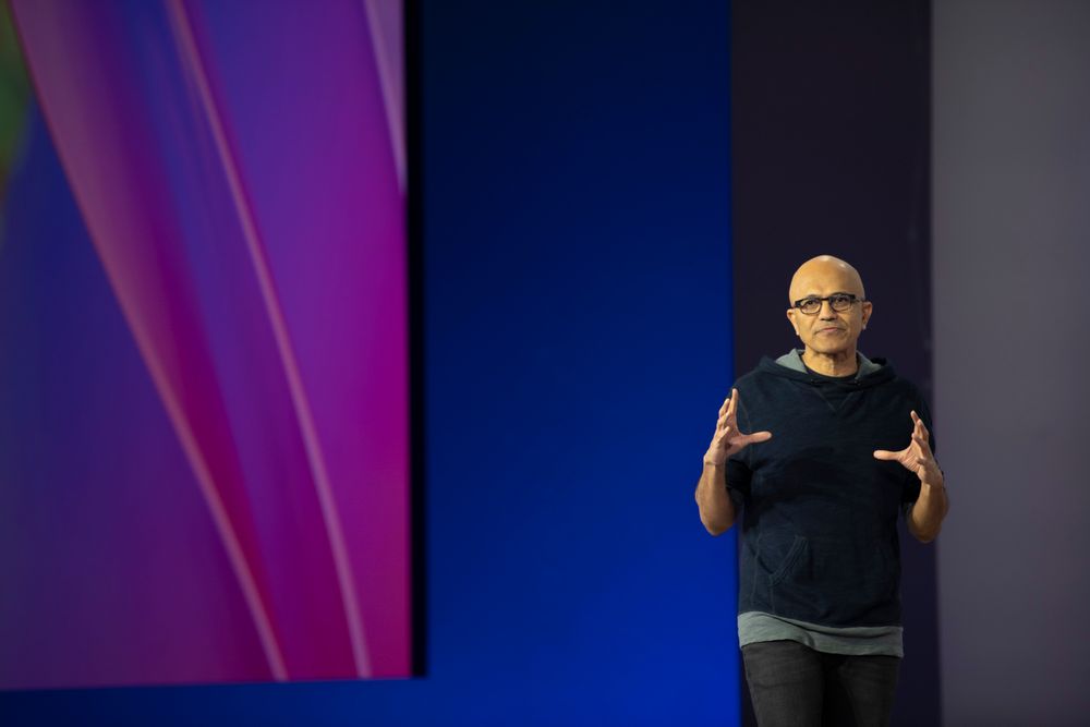 Speaker presenting on stage with colorful backdrop at tech conference.
