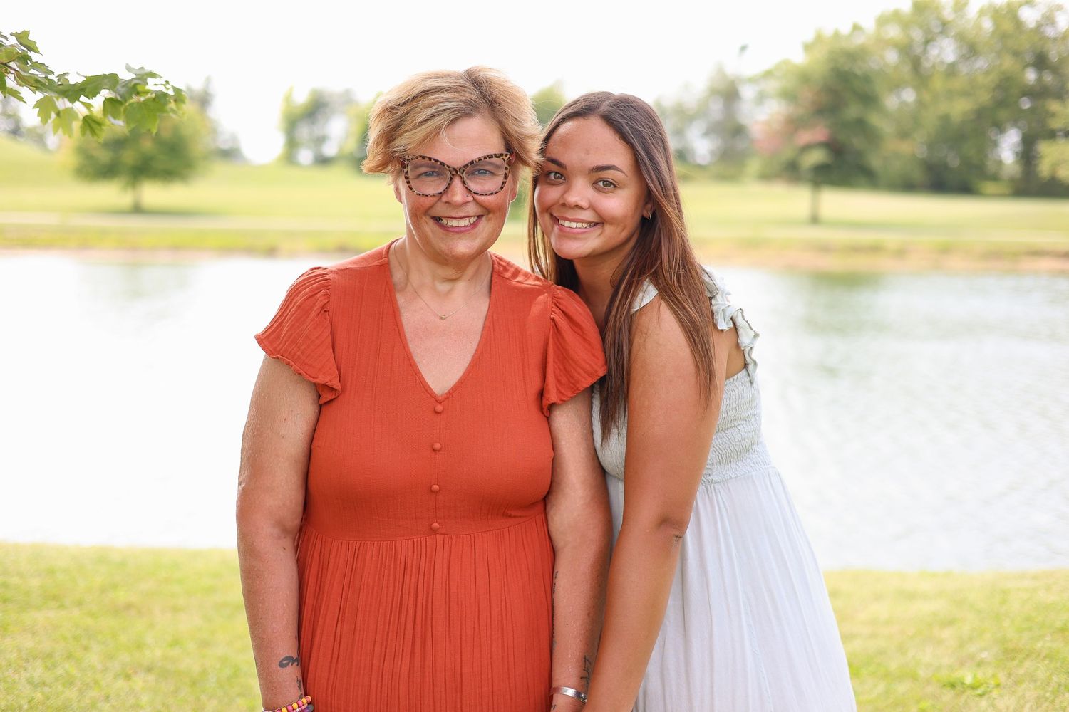 Two people share a warm moment together by a lake on a sunny summer day.