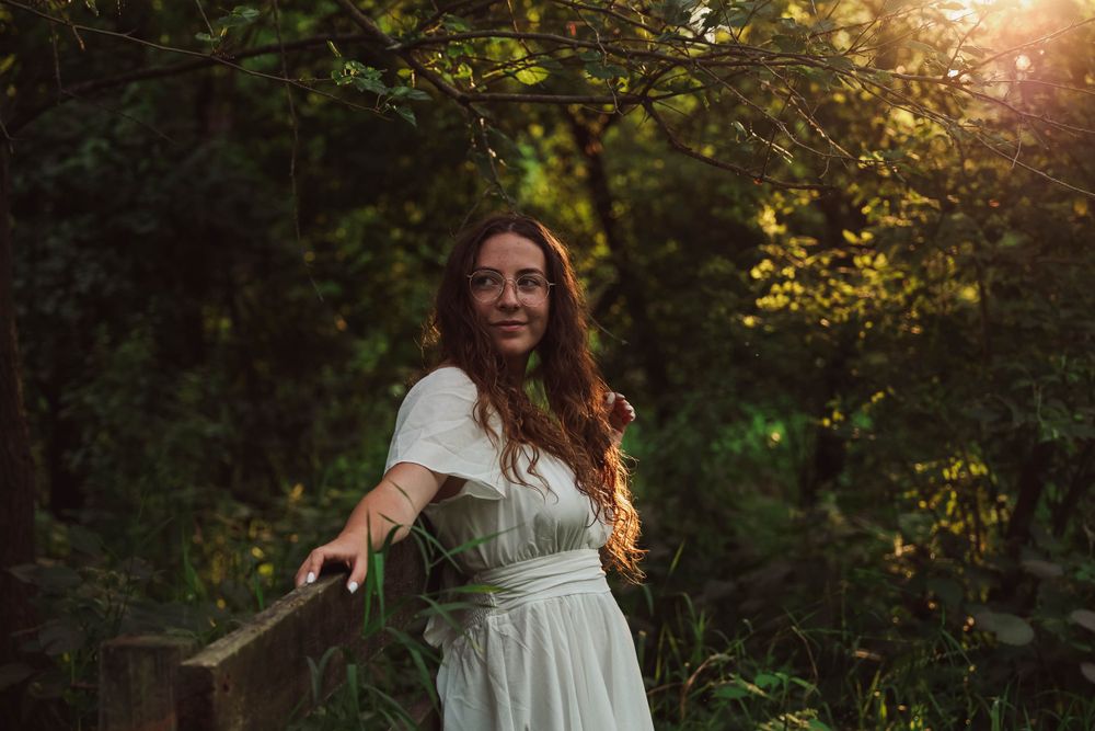 Someone in a white summer dress spins playfully in a lush garden setting.
