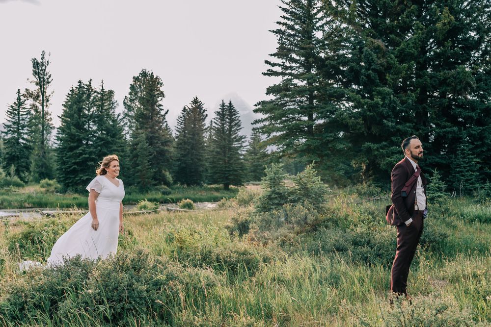 Bride and groom standing apart in a mountain meadow in the Teton Mountains waiting for their first look