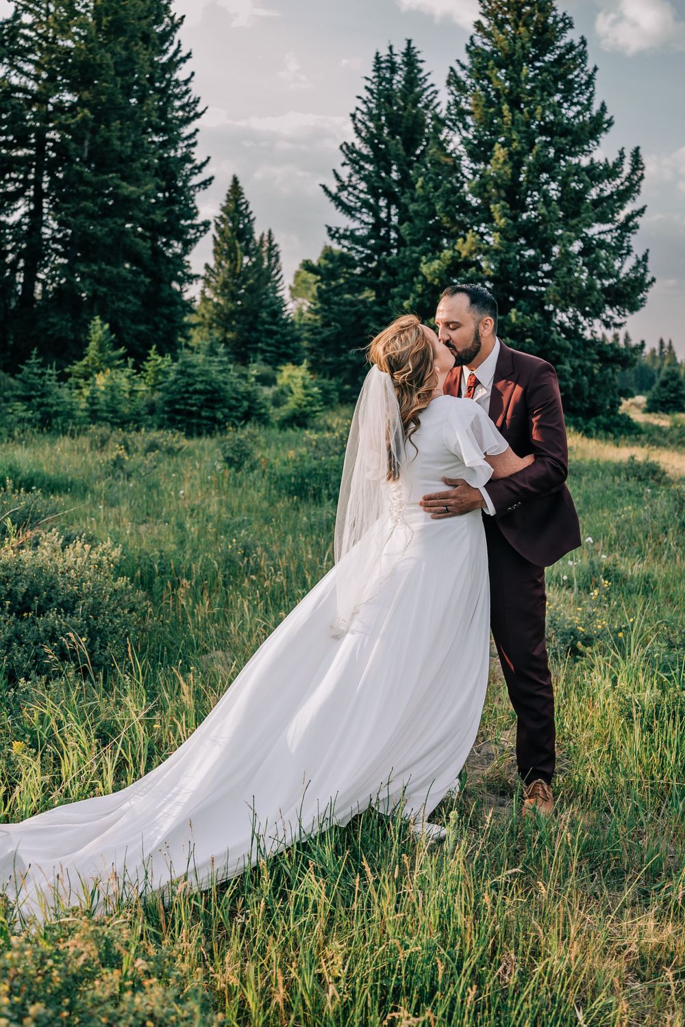 Bride and groom sharing a tender embrace in a mountain field in the Teton Mountains