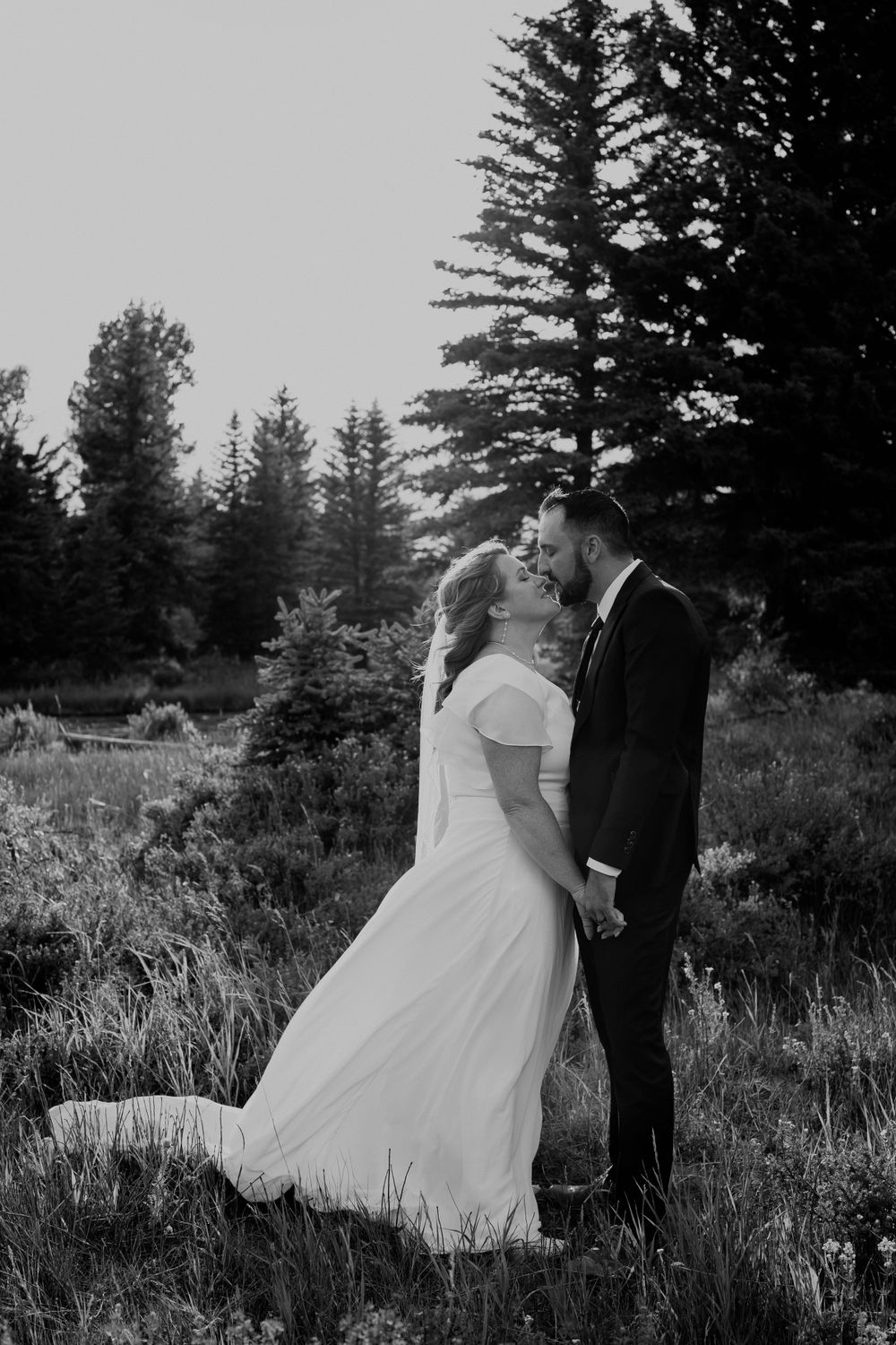 Bride and groom sharing a romantic kiss with a Teton mountain field stretching out behind them