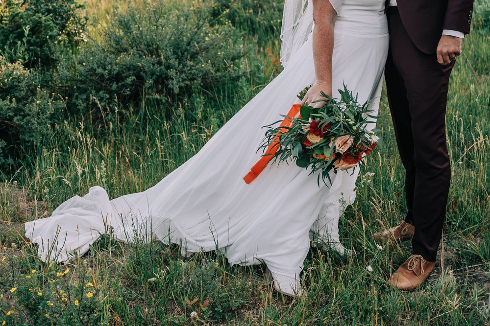 Close up of the bride and groom's feet showing off wedding dress bottom and bouquet