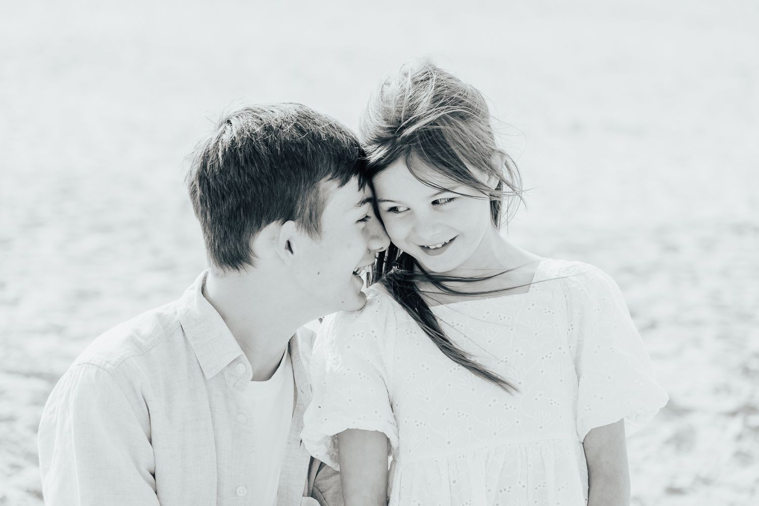 A black and white photo of two siblings chatting together.