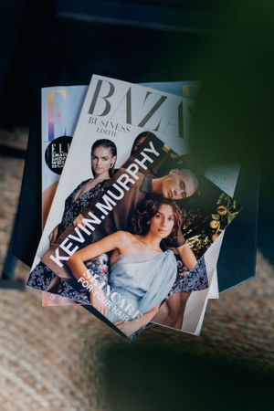 Modebladen met BVZ en andere publicaties, gestapeld op een houten oppervlak.
