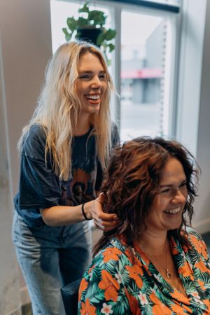 Haarstylingsessie met een vrolijke interactie tijdens de salonbehandeling.
