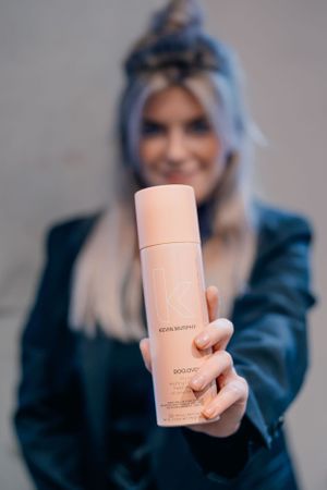 Roze Kevin Murphy haarproductfles gepresenteerd tegen een wazige achtergrond.