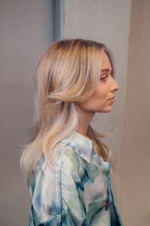 Zijprofiel van blond haar gestyled in lagen, gecombineerd met een blauw-witte tie-dye top.