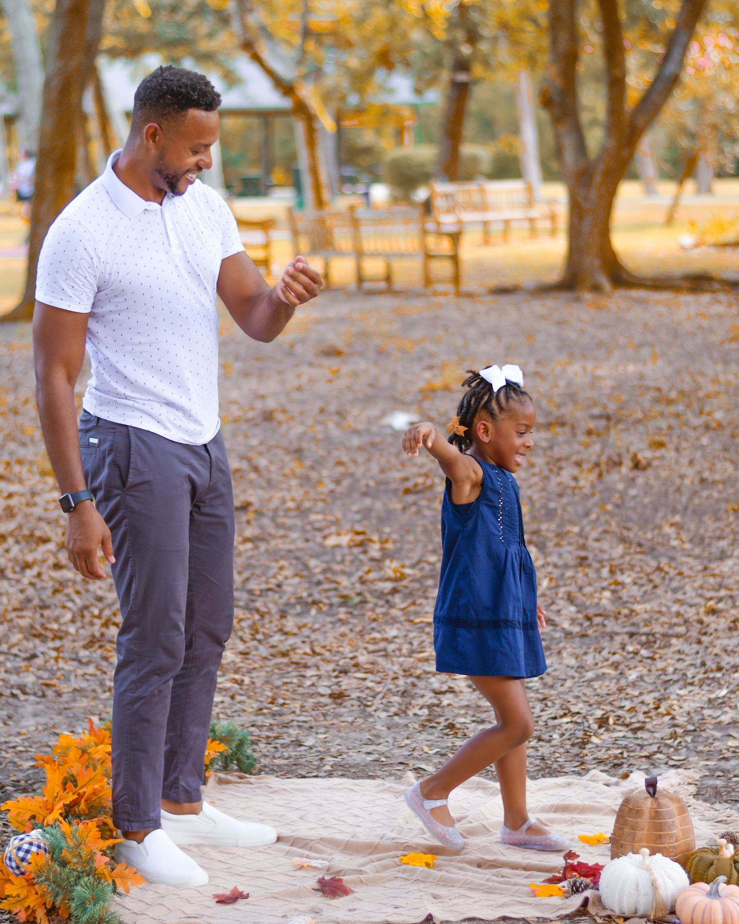 A family walks together on a fall day path decorated with pumpkins and autumn foliage.