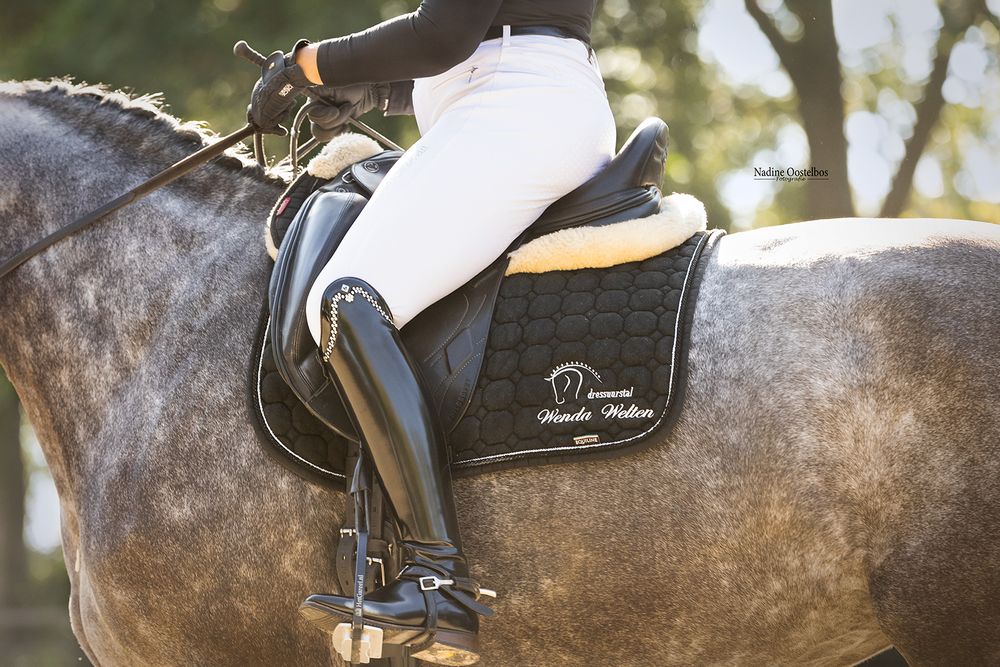 Close-up view of gray horse's muscular body with dressage saddle during competition.