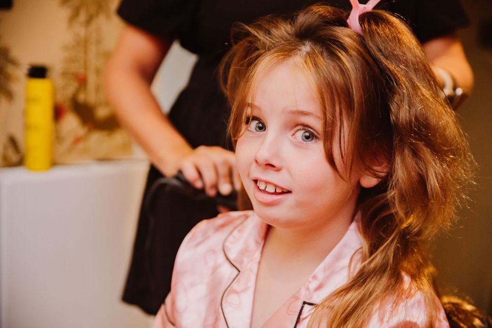 A young bridesmaid is having her hair done at The Bull Hotel in Bridport. The photograph is candid and documentary