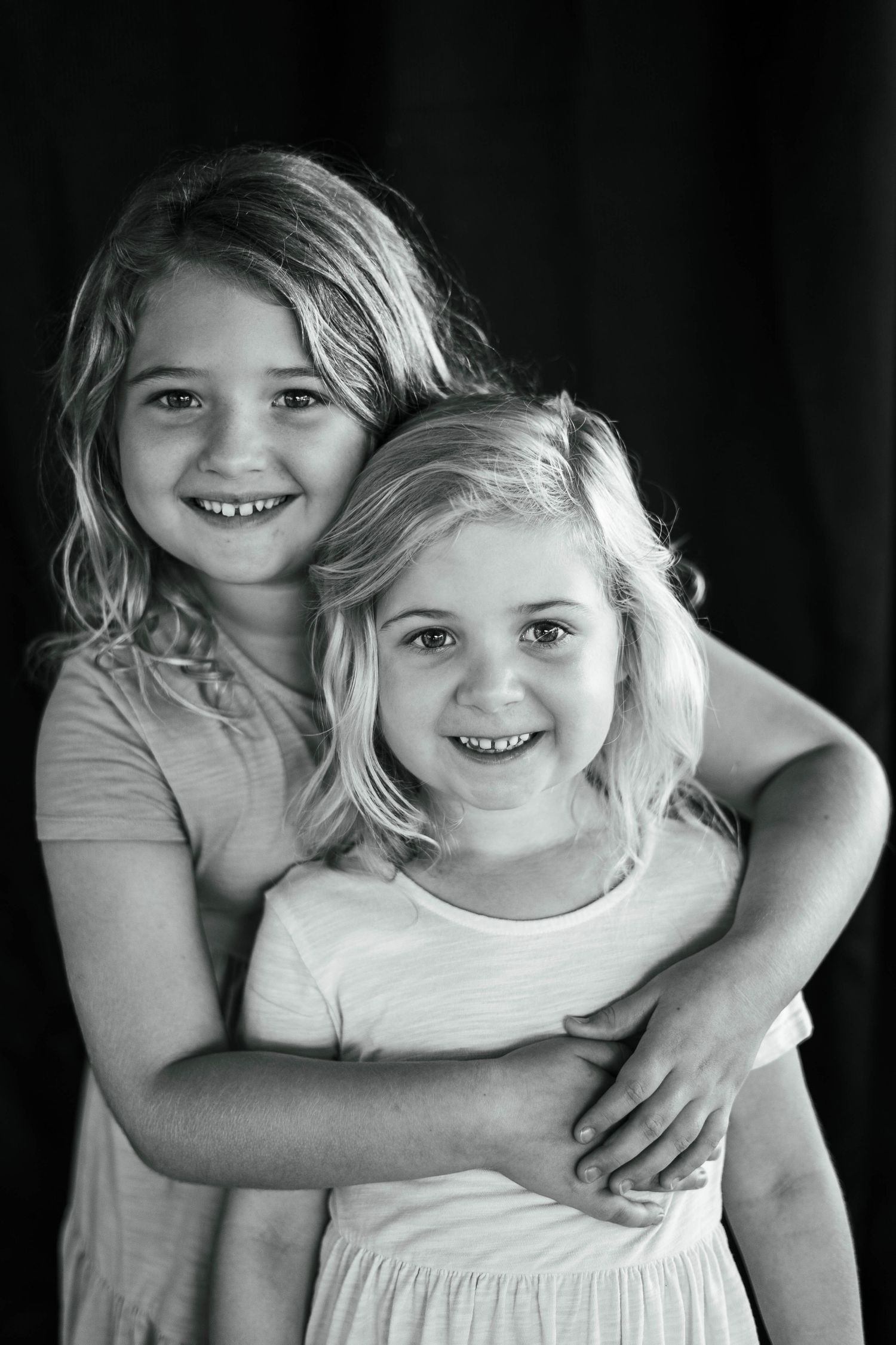 Sisters snuggling close for a sibling picture at melbournes kids village family portraits