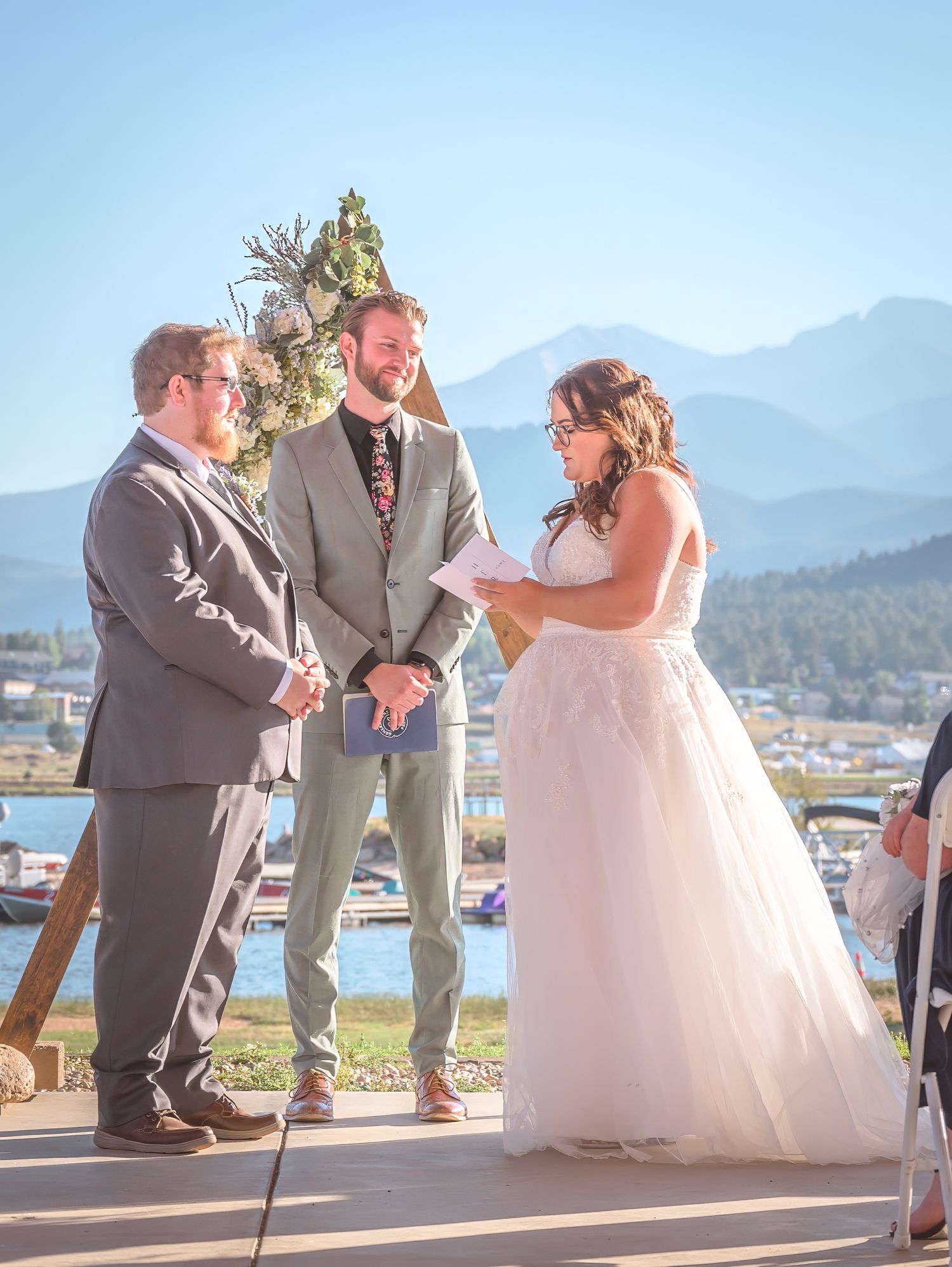 Outdoor wedding ceremony with mountain backdrop and lake scenery on a sunny day in Estes Park.