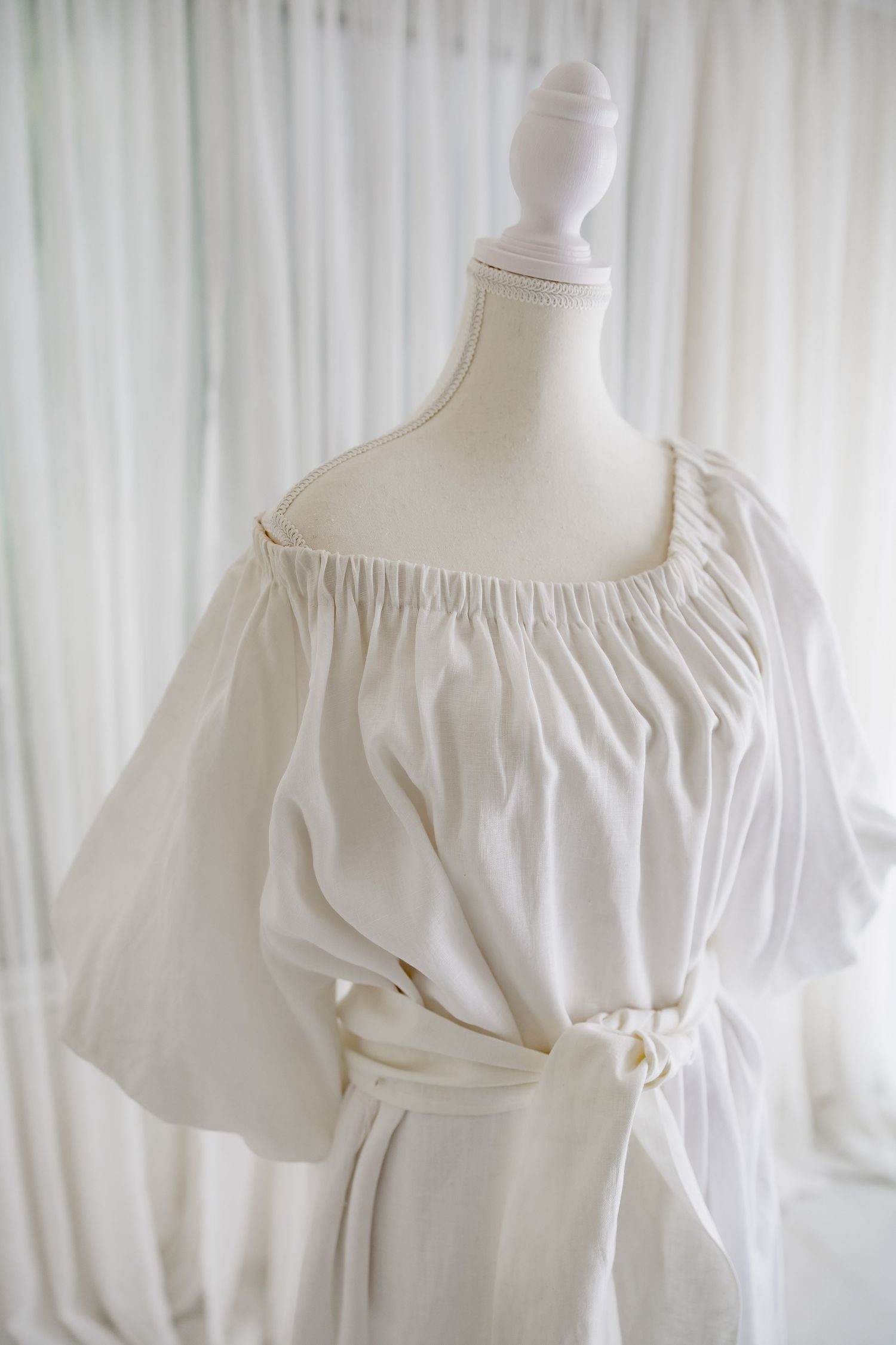 Detail shot of gathered neckline and puff sleeve on white cotton dress.