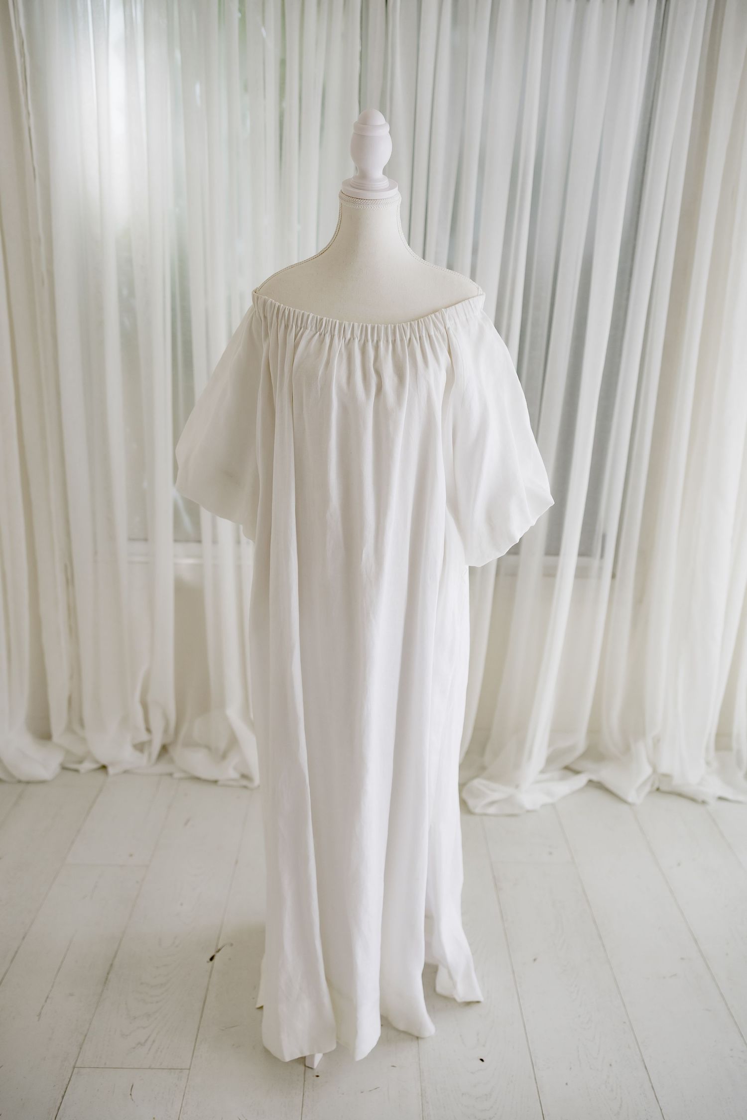 White flowy maxi dress with balloon sleeves displayed on mannequin.