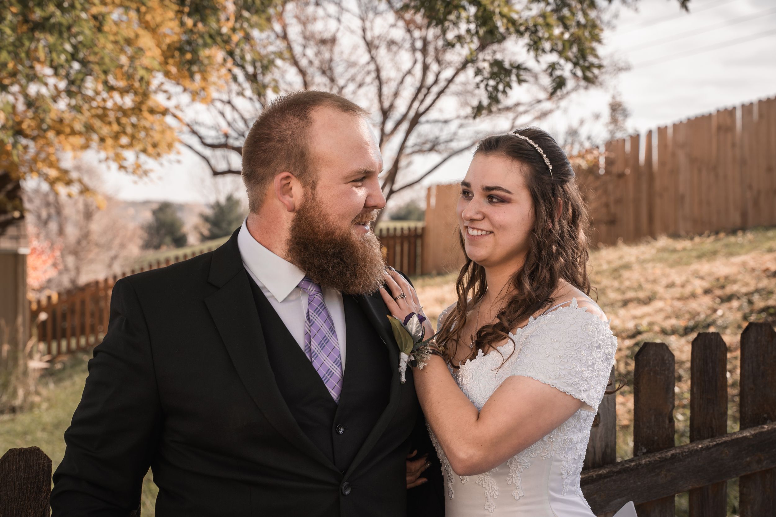 A couple shares a lighthearted moment during their wedding photos outdoors.
