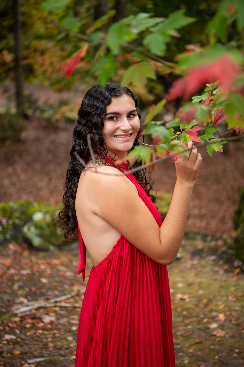 Red halter dress photographed among fall foliage and maple leaves.