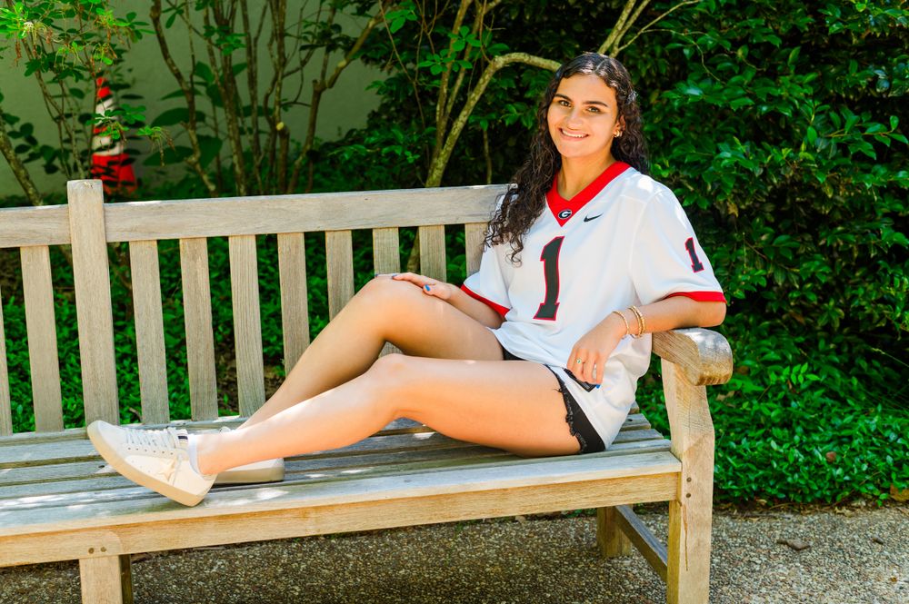 A casual summer outfit with red scarf accessory on a wooden bench in a garden setting.
