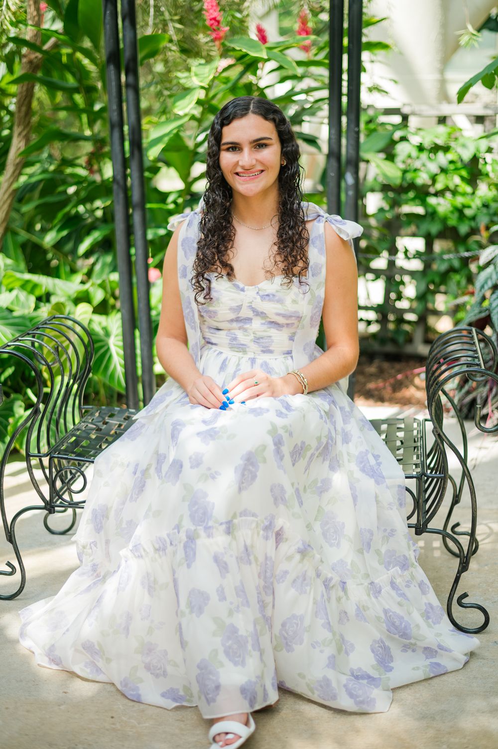 A floral lavender and white dress photographed in a lush garden gazebo setting.