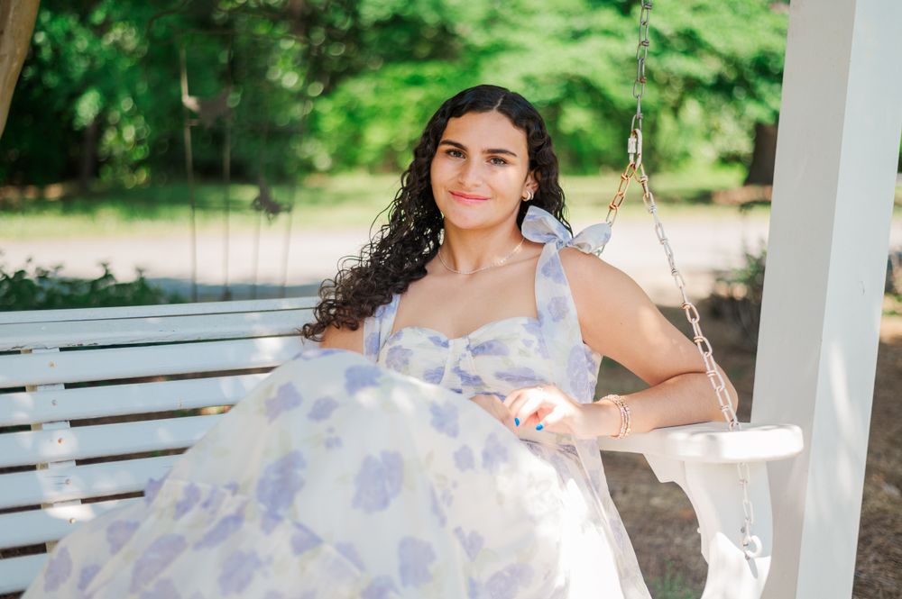 Relaxing on an outdoor swing in an elegant white and lavender dress.
