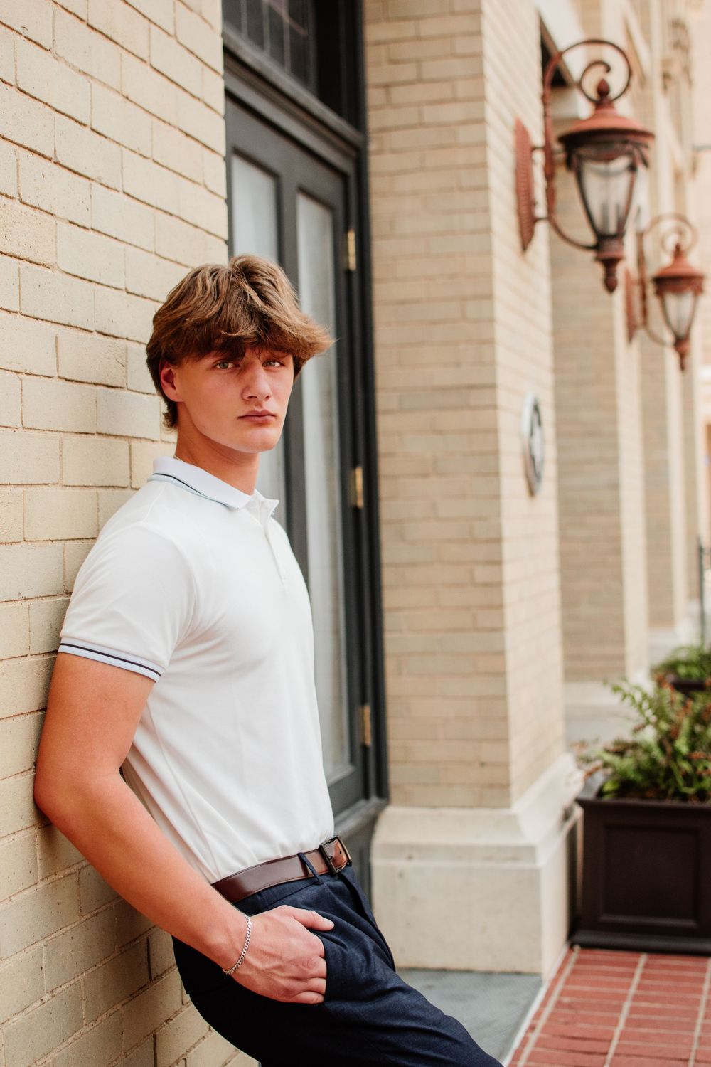 Urban Senior portrait of young man outdoors in Downtown Fort Worth standing against a brick building