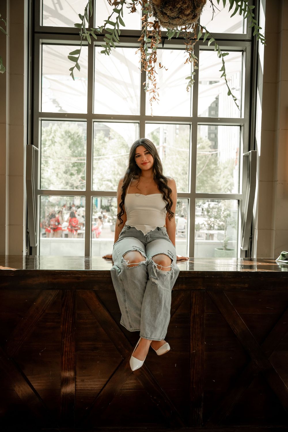 Senior girl portraits in downtown Fort Worth, Texas taken by Jaime Layne Photography in front of window with hanging greenery