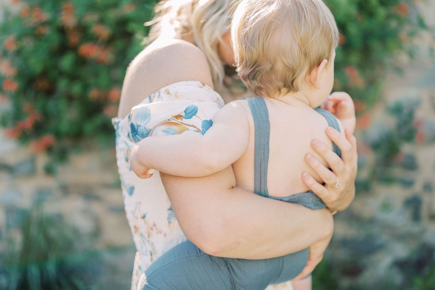 A warm embrace captured in soft sunlight against a garden backdrop.