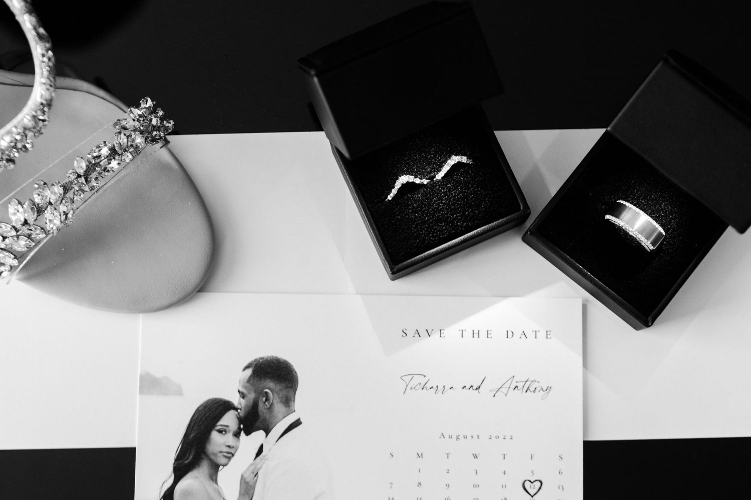 Wedding save the date card with rings and jewelry on white surface.
