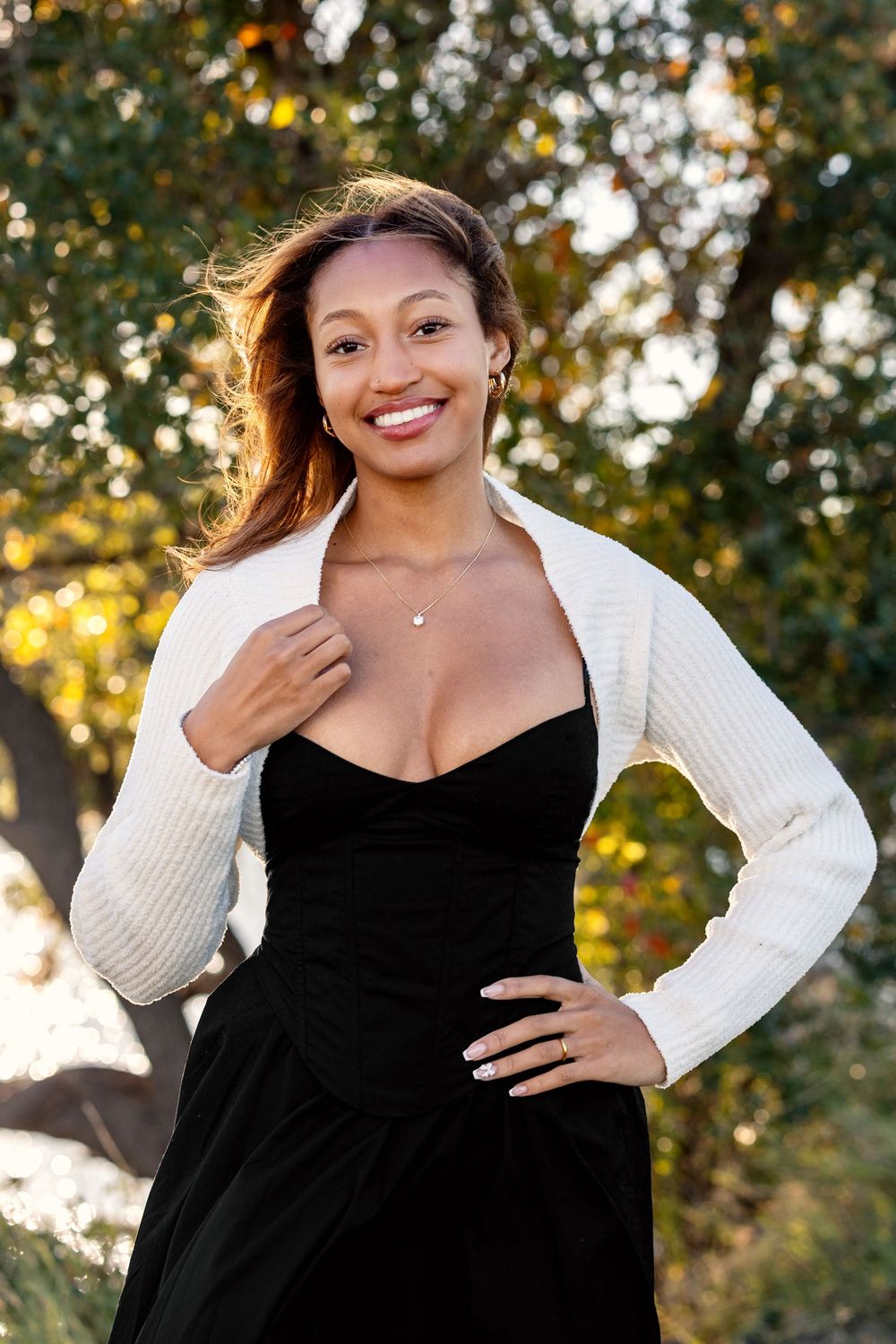 A series of four outdoor portraits showing someone in a black dress and white cardigan against a sunlit natural background.