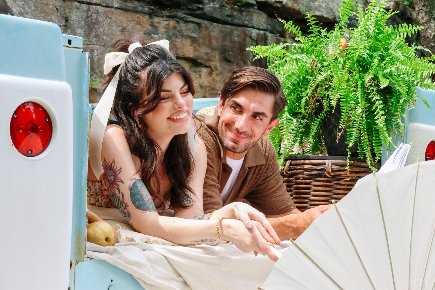 Happy couple relaxing together in the back of a vintage light blue truck with a fern plant.