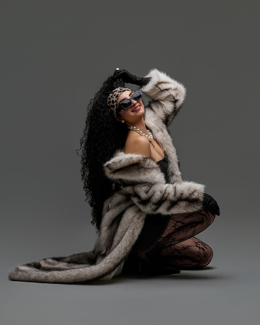 A model in a luxurious fur coat and sunglasses poses dramatically against a gray studio backdrop in a series of artistic shots.