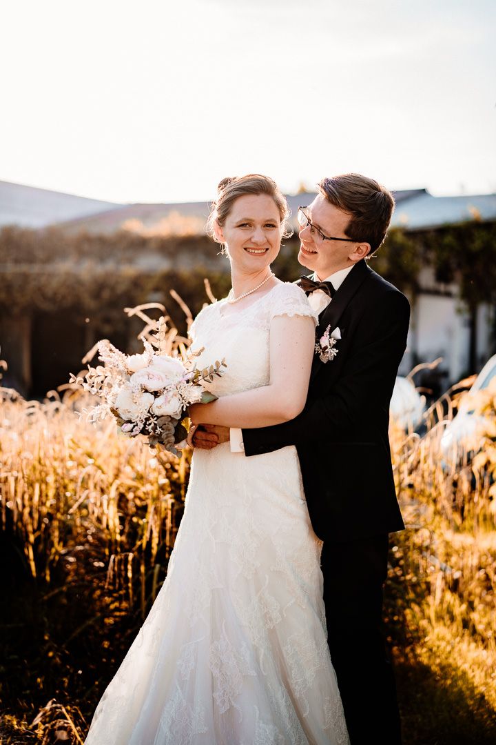 A wedding couple shares a romantic moment in a golden field at sunset.