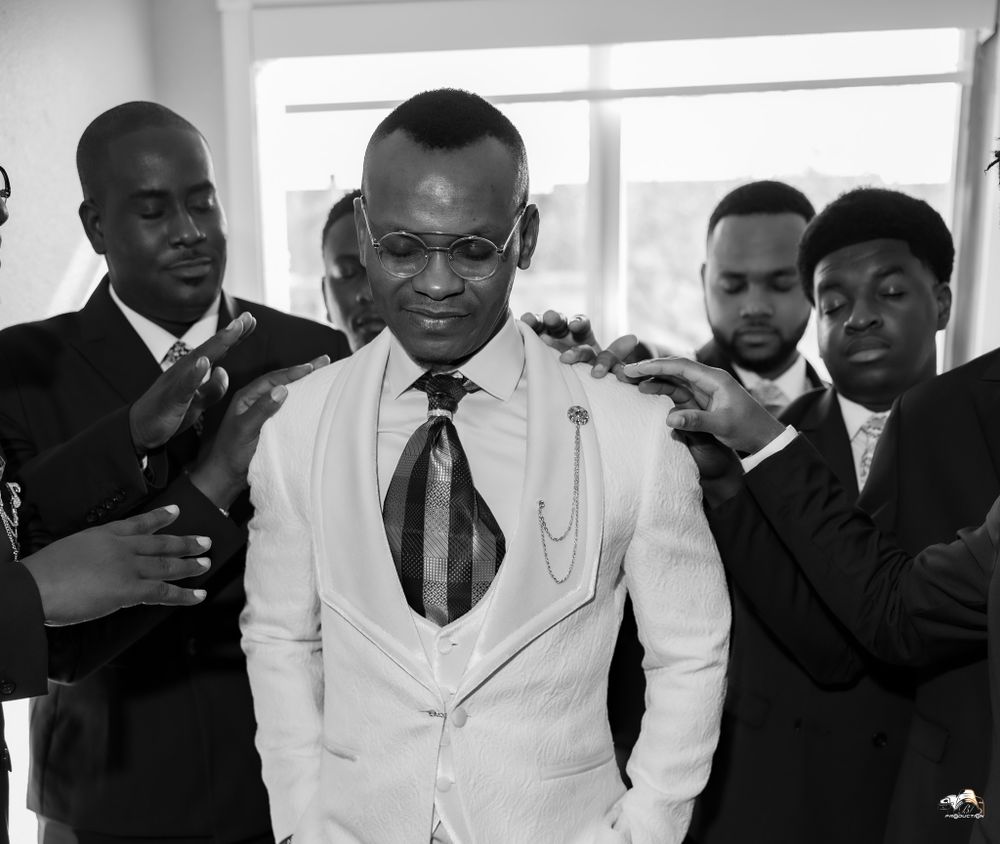 Black and white portrait of groom with groomsmen during wedding preparation.