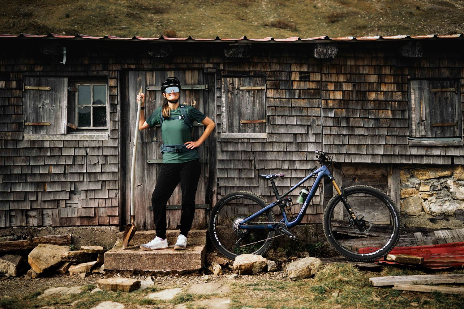 A rustic wooden building with weathered shingles and a vintage bicycle leaning against the wall.