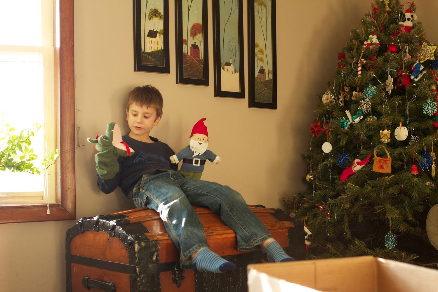 a young boy plays with puppets, christmas tree in background