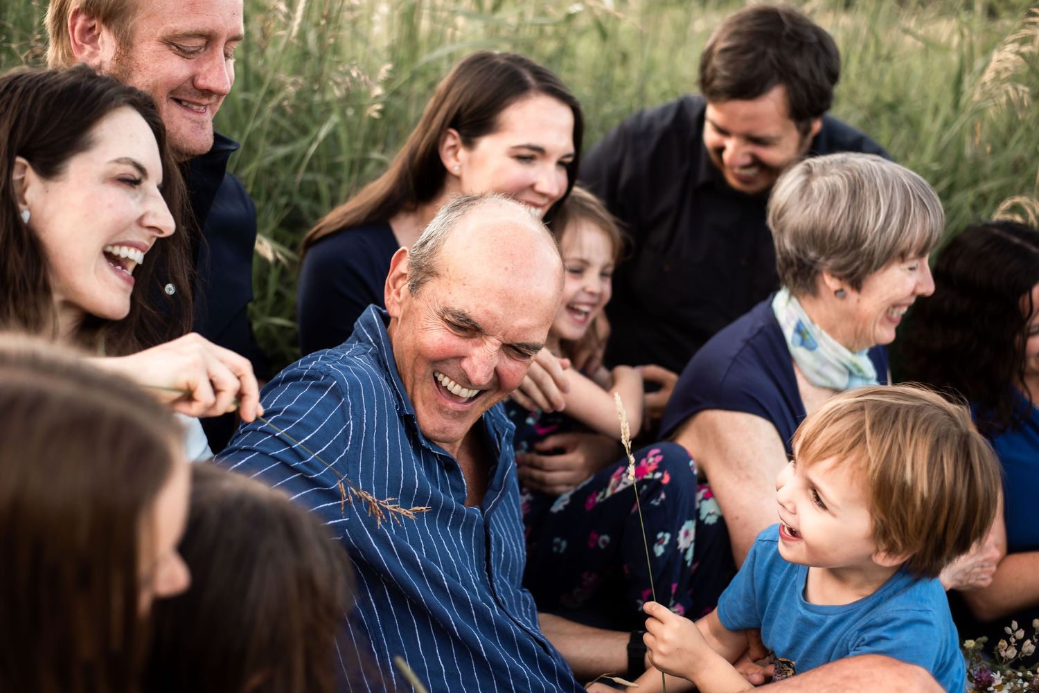 A multi-generational family shares laughter during an outdoor photo session.