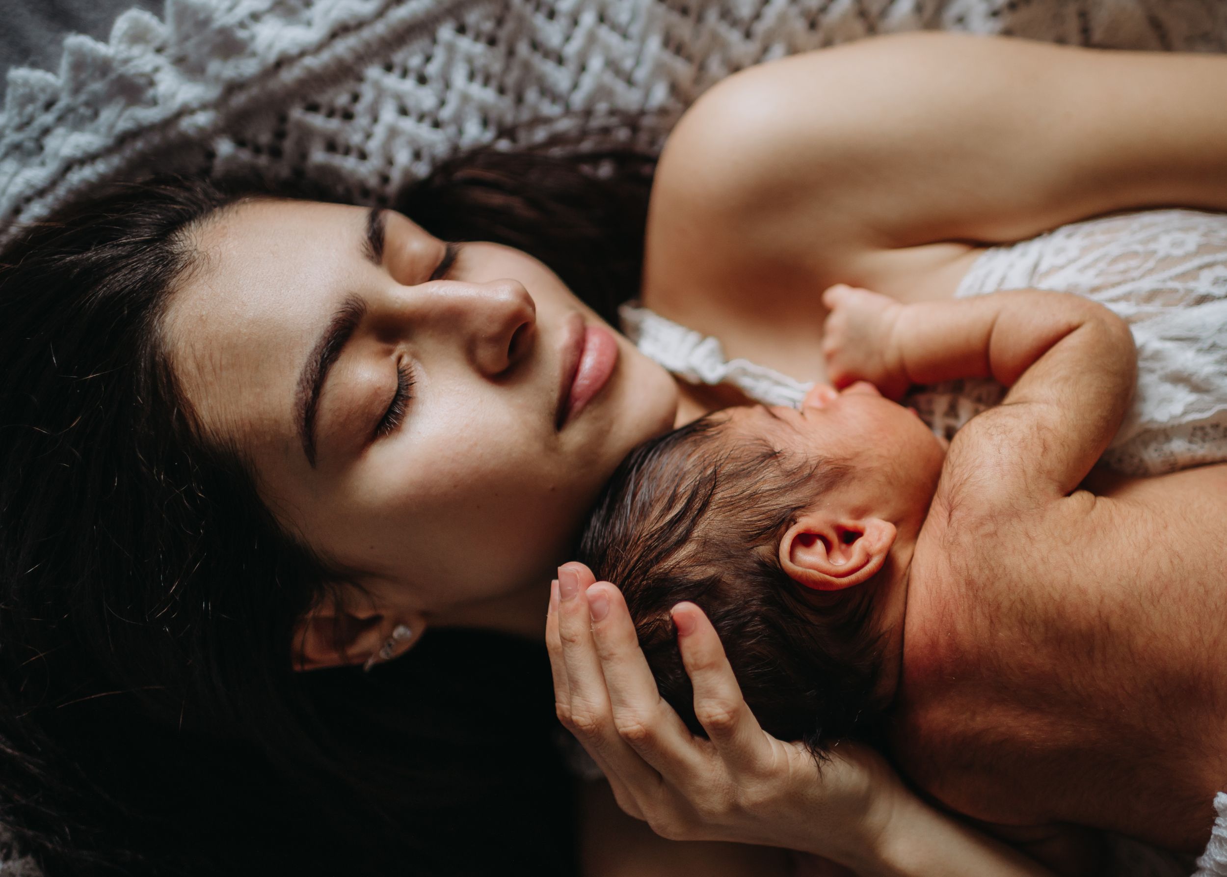 A mother and her new-born laying down peacefully during their in-home lifestyle photo session in kent