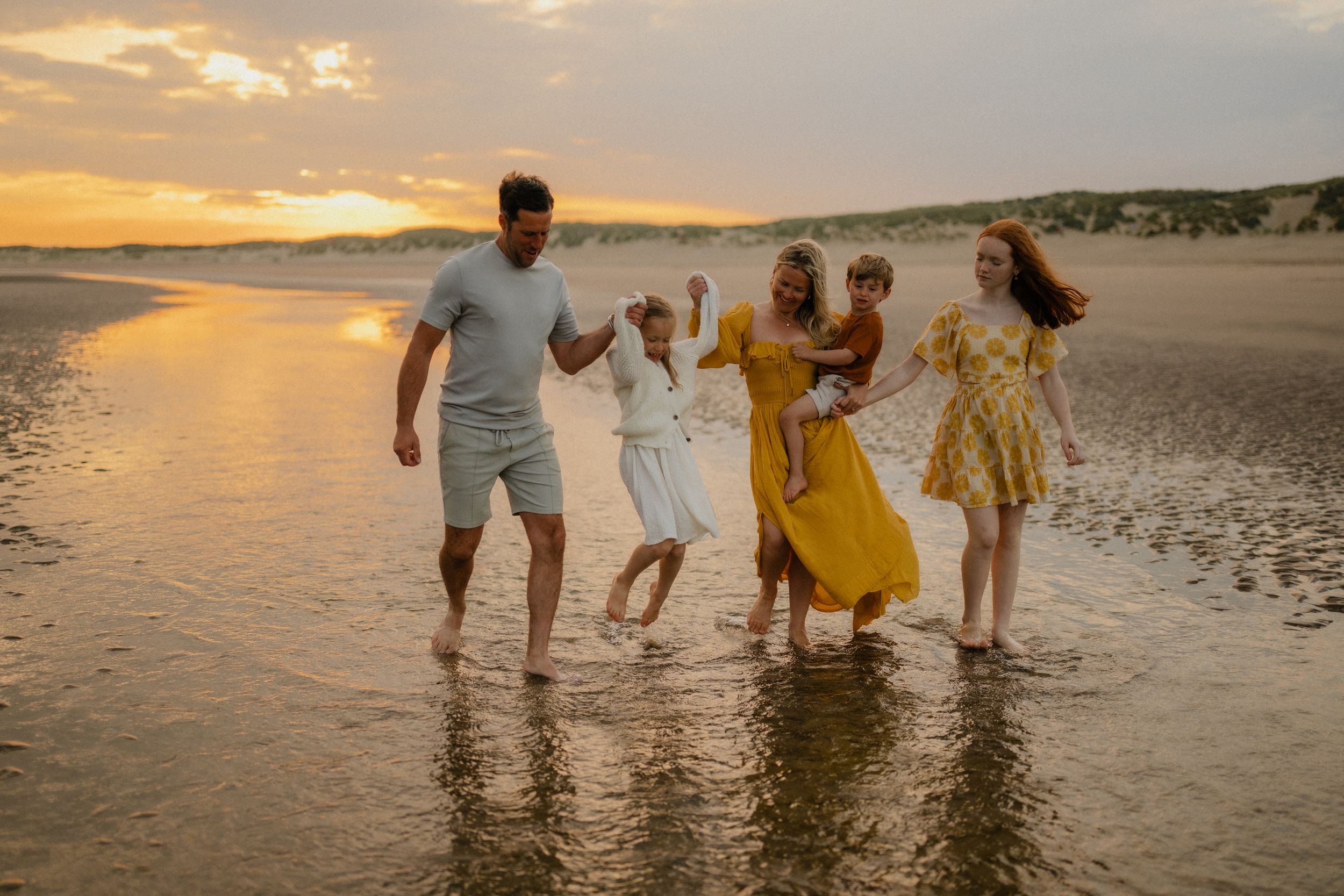 A family of 5 walking on the beach at sunset during a photo session in Camber sands Kent with family photographer Forever Ours Photography