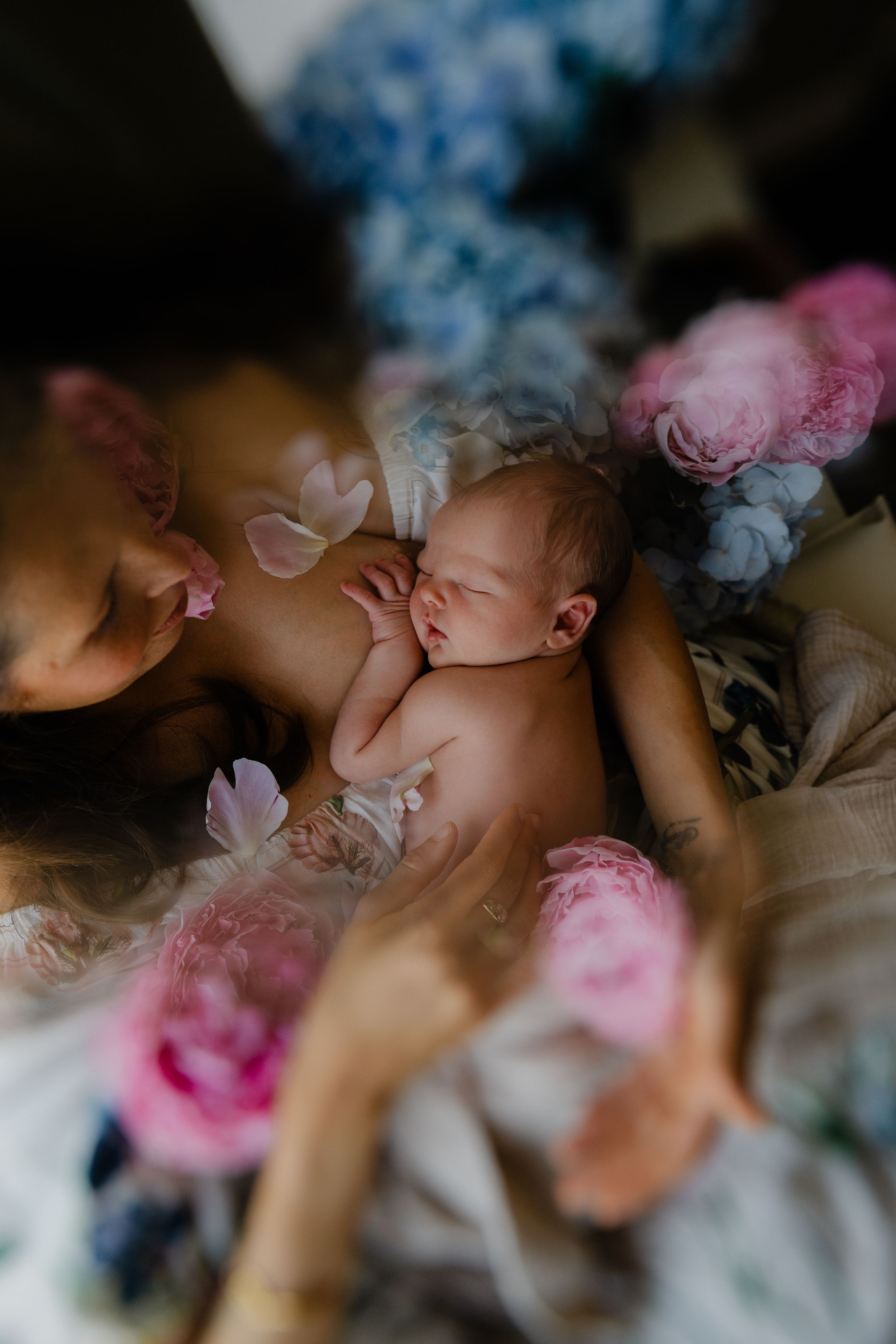 a new born sleeping in his mother's arms while being surrounded by flowers