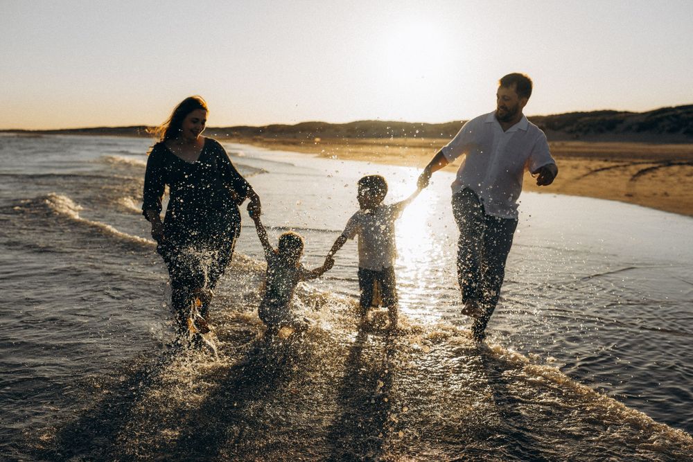 a family of four splashing in the water in Camber sands, UK