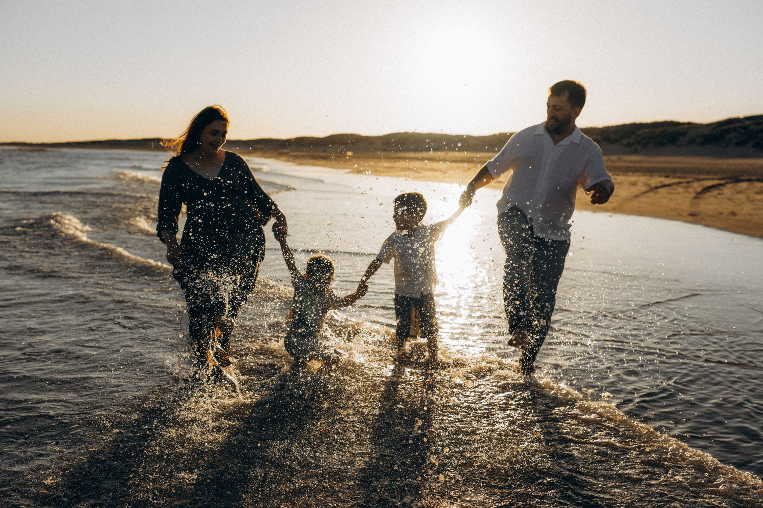 a family of four splashing in the water in Camber sands, UK