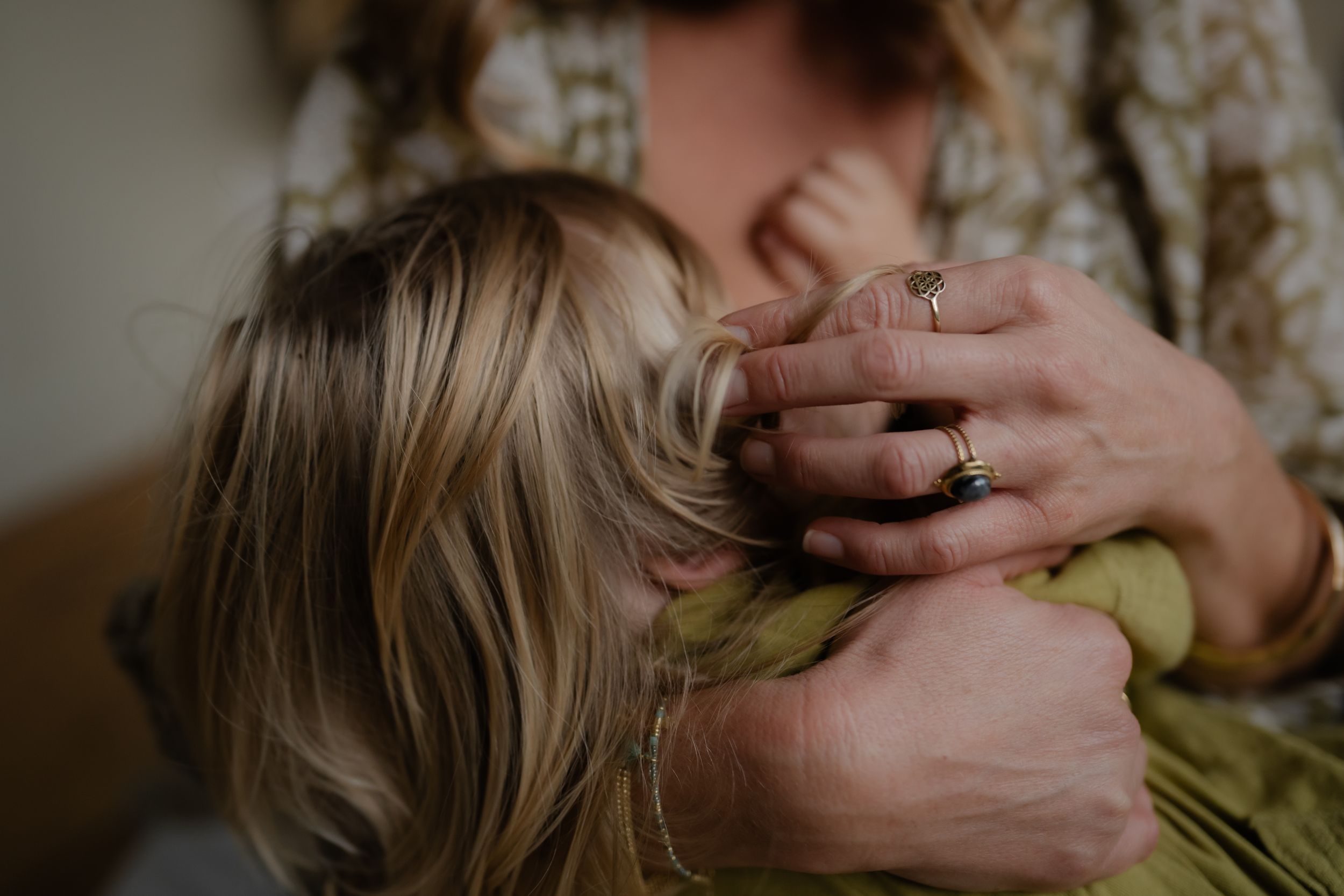 A close-up of a mother's hands playing with her boy's hair while he is nursing