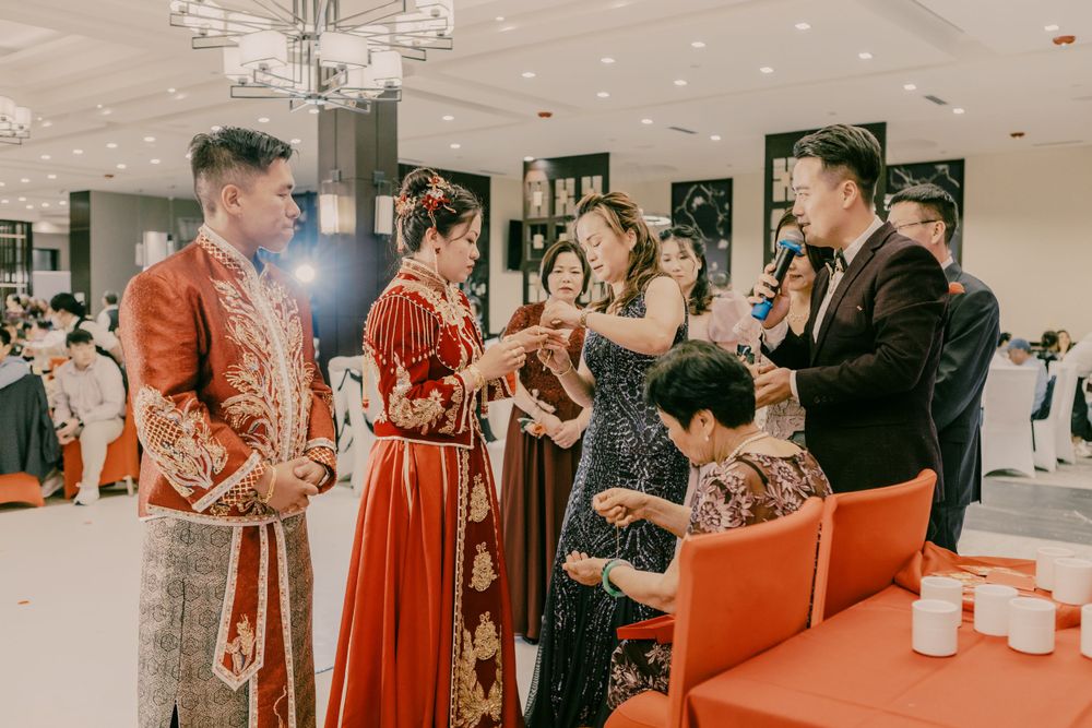 Wedding reception gathering with guests in formal attire and traditional Chinese elements.