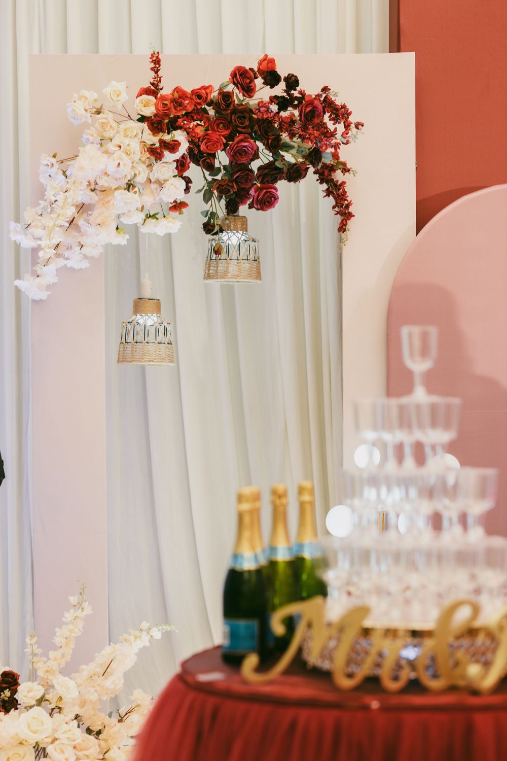 Elegant wedding decor featuring red and white floral arrangements with champagne tower setup.