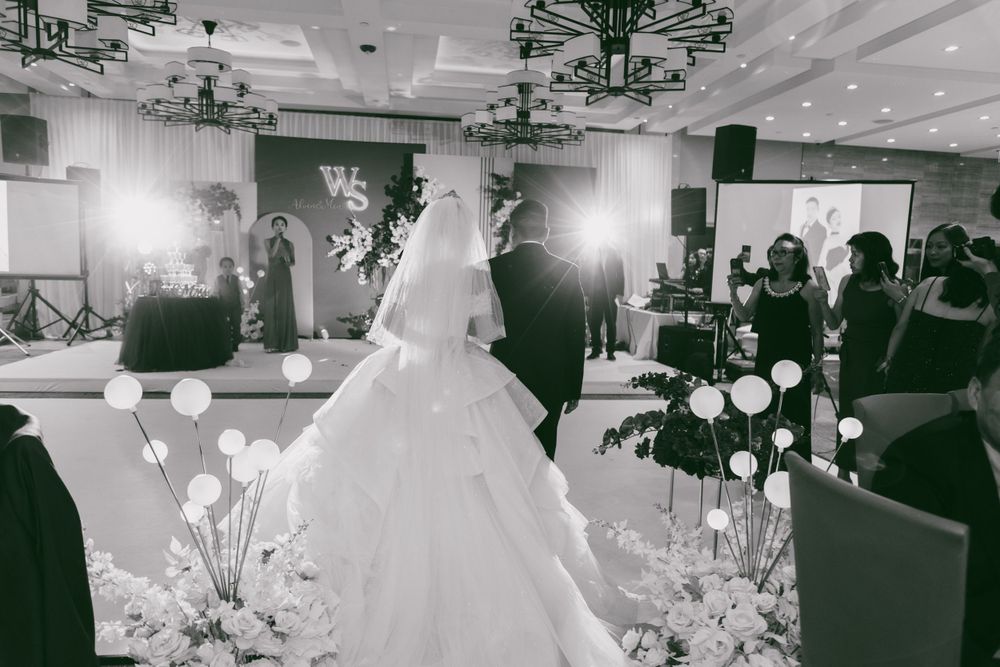 Wedding celebration in an elegant ballroom decorated with white balloons and chandeliers.