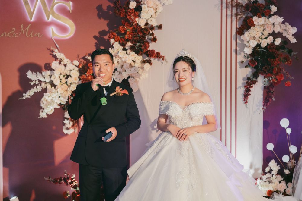 Wedding ceremony backdrop with WS monogram, red and white floral arrangements, and soft lighting.