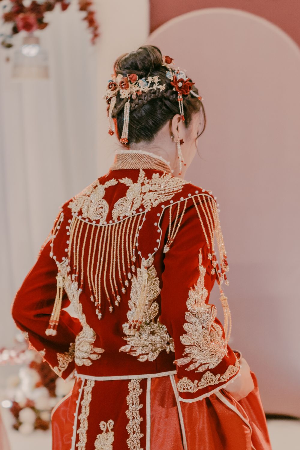 Traditional red Chinese wedding dress with intricate white lace detailing and floral hair accessories.
