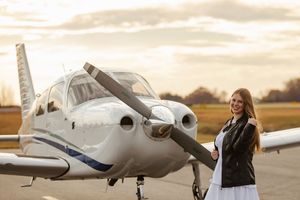Small private jet parked on tarmac during golden sunset at airport with people walking nearby.