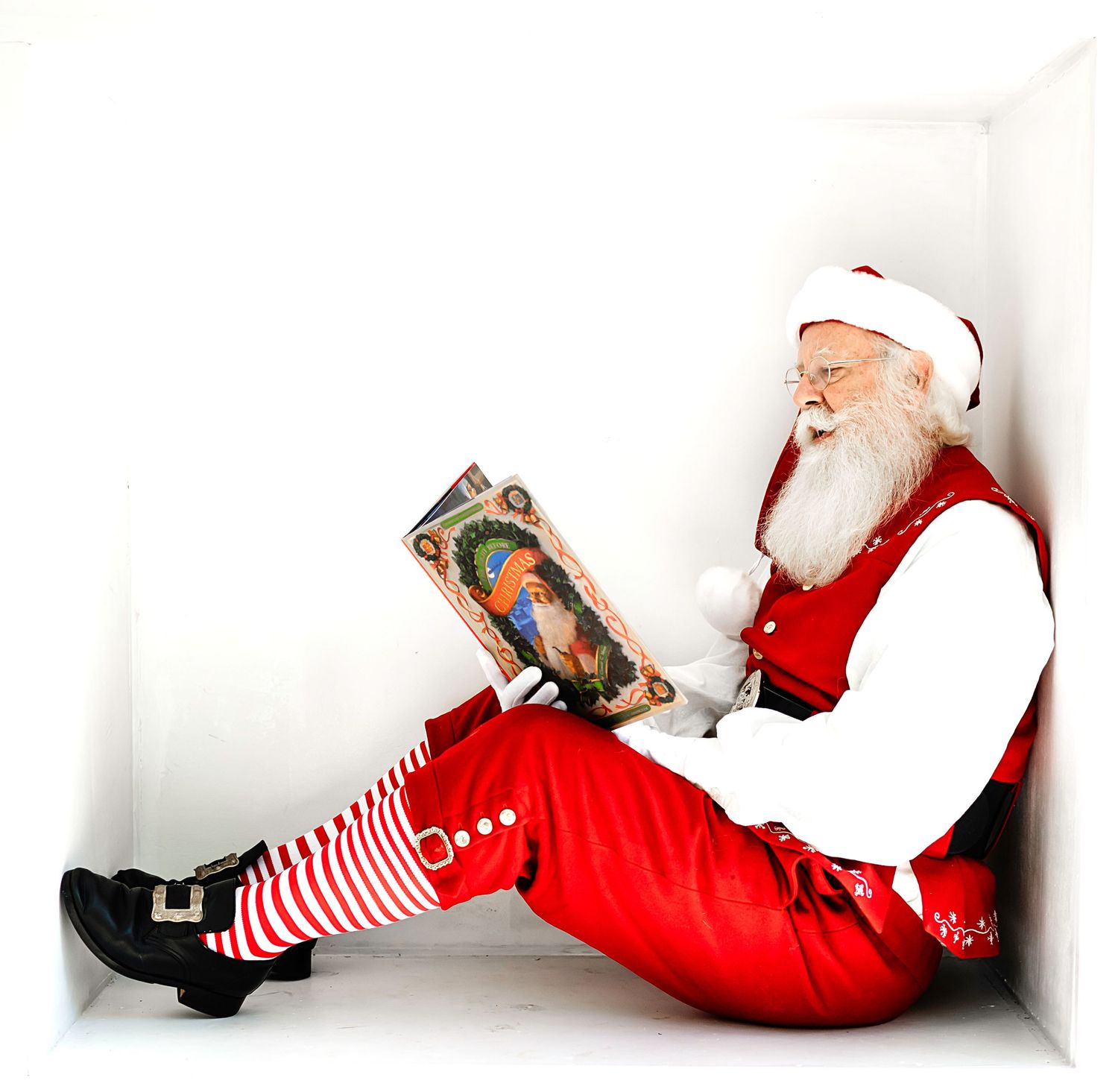 Traditional holiday Santa in red and white outfit relaxing with a vintage nutcracker decoration.