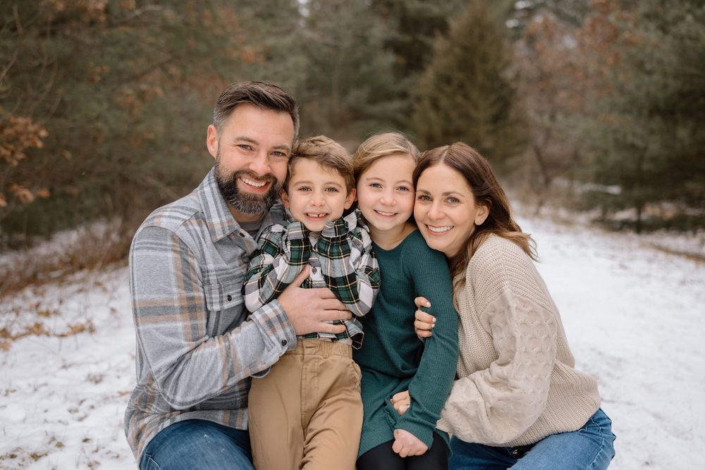A loving family embraces while taking winter portraits in the snow.